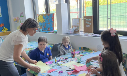 Učiteljica priča učenicima koji sede za stolom