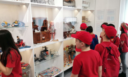 Učenici razgledaju drevne igračke u izlogu muzeja