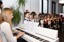 Učiteljica za klavirom svira horske pesme za decu