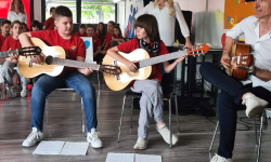 Učenici sviraju gitaru sa učiteljem